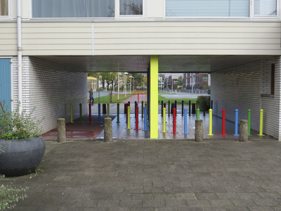 906641 Gezicht door een onderdoorgang met kleurige paaltjes onder een flatgebouw aan de Oranjerivierdreef te Utrecht, ...